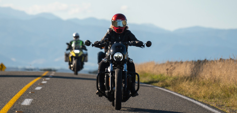 Two people riding motorbikes in a rural setting.