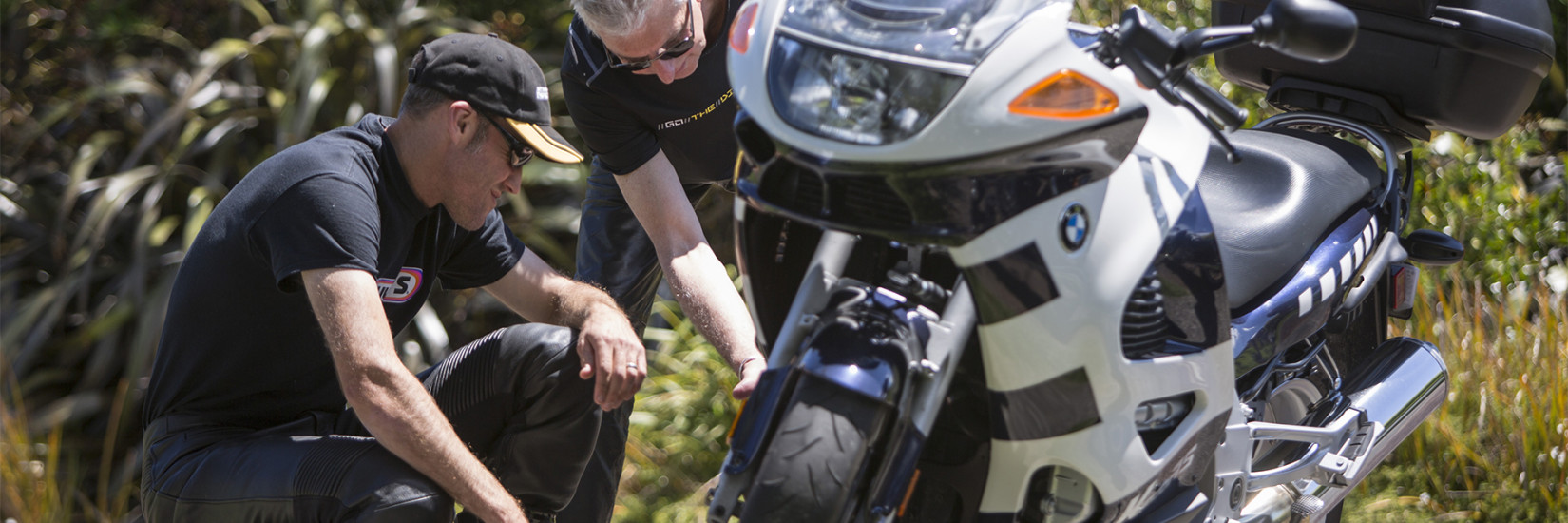 Two men inspecting rear of motorbike