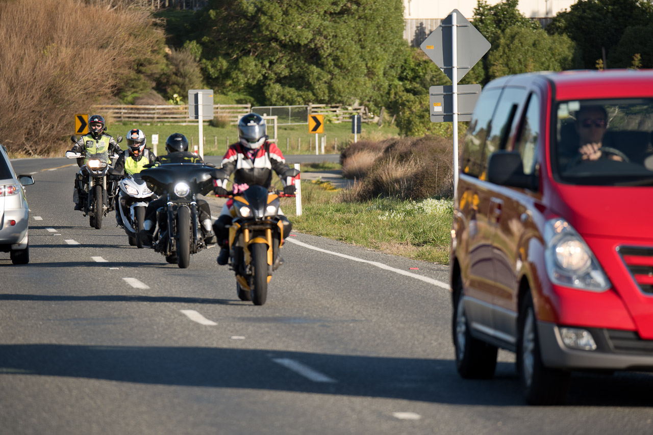 Queue of bikes driving behind van 