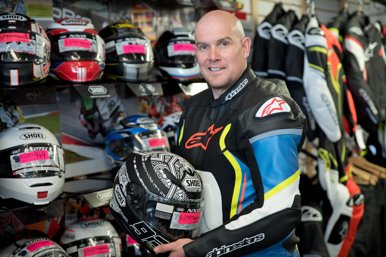 Man in Motorcyle Gear shop, holding helmet