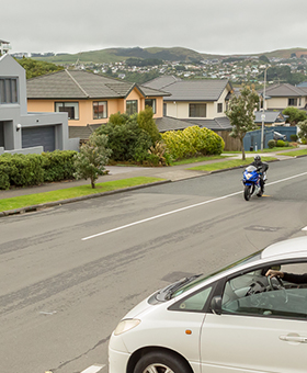 Motorcyclist riding through a T intersection with a car on a left road