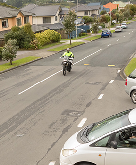 Motorcyclist riding through a T intersection with a car on a left road