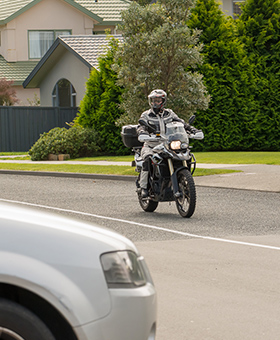 Bike riding straight with car on side street to the right